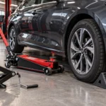 Cric hydraulique roulant et cric à ciseaux près d'une voiture dans un atelier automobile